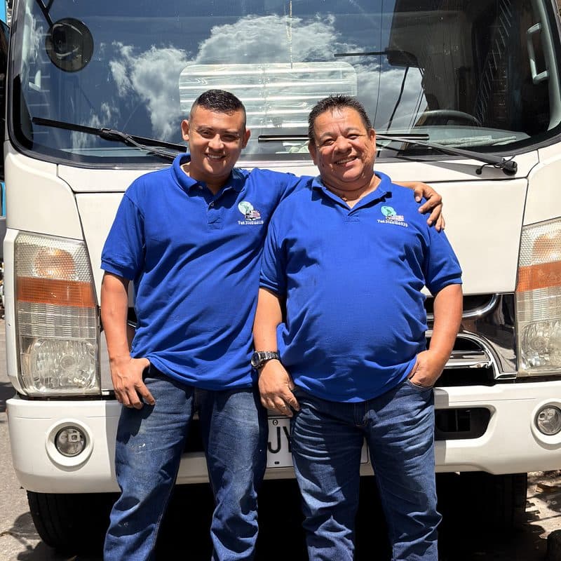 Dos colaboradores de Transcolombia S.A.S. frente a un camión de la flota